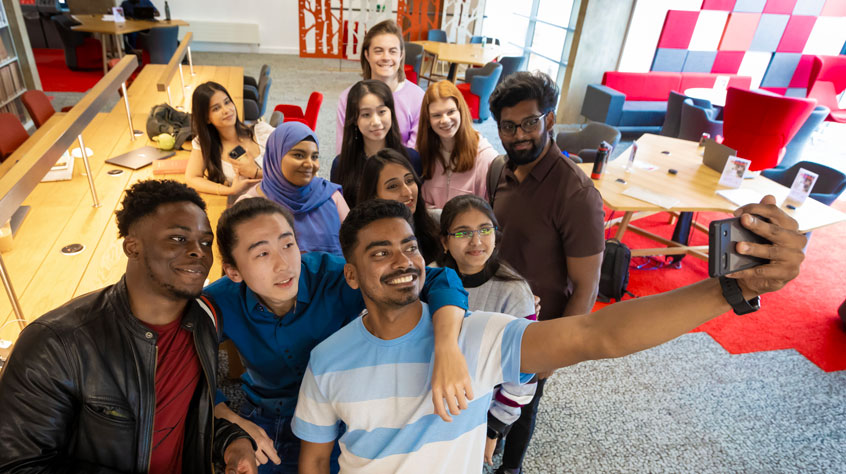 A group of students taking a selfie in the library.