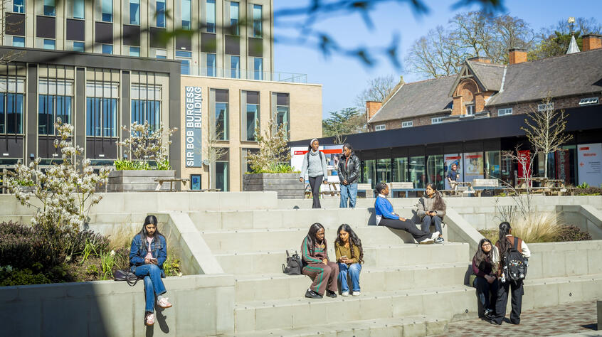Students sitting outside on the steps on University of Leicester campus.