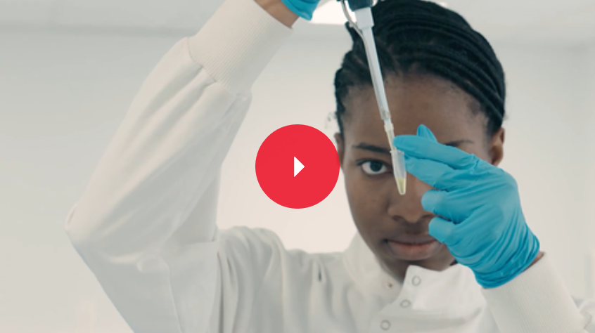 Biological sciences student in a lab, wearing a white coat and concentrating on using a pippet