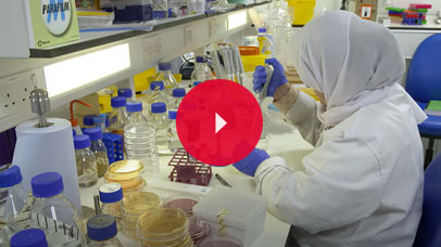 Person in a lab coat, using a pipette in a lab.