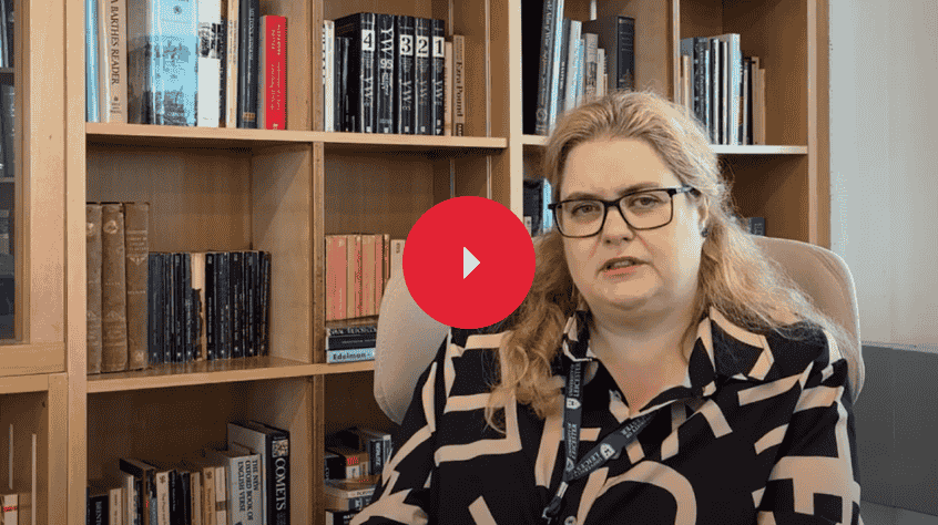 Dr Anna Claydon sat in an office with a bookcase behind her and talking to the camera