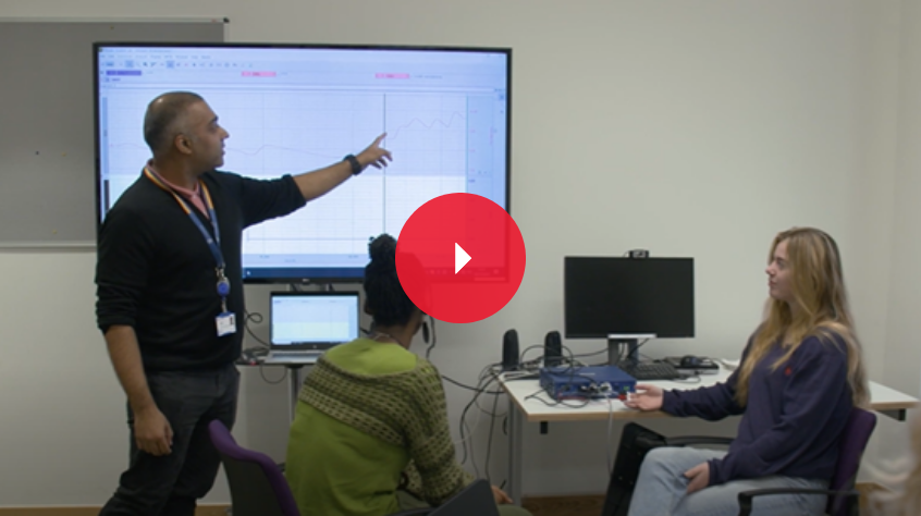 Students and a lecturer in a classroom with a projected screen
