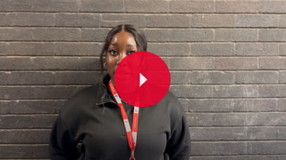 Student talking to camera with a brick wall behind her.