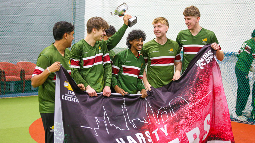 Varsity 2026 team wearing their green kit, holding up the Varsity flag and a trophy.