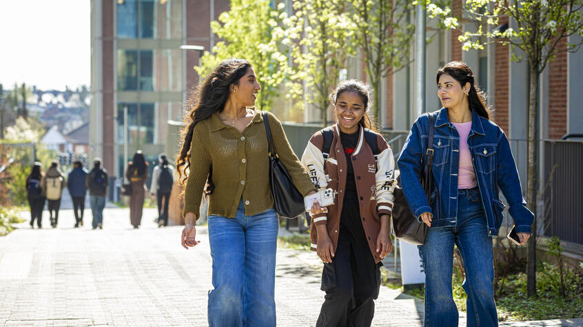 Three female students walking and talking on University of Leicester campus.
