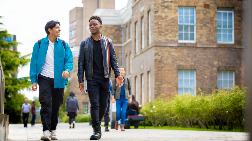 Student walking past the Fielding Johnson building on University of Leicester campus