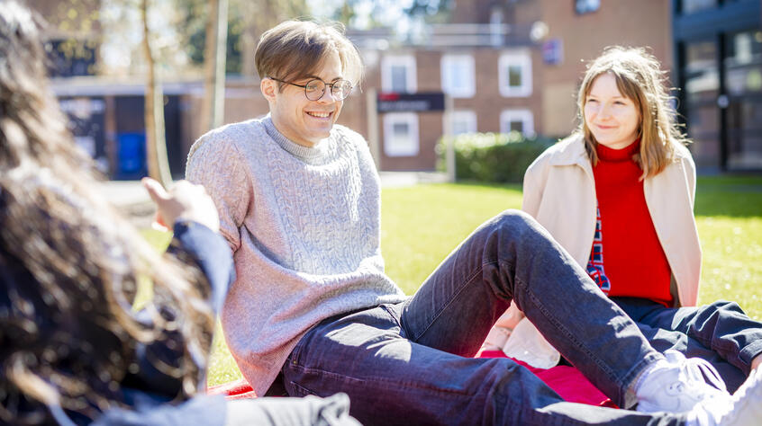 People sitting on the grass outside on a sunny day. 