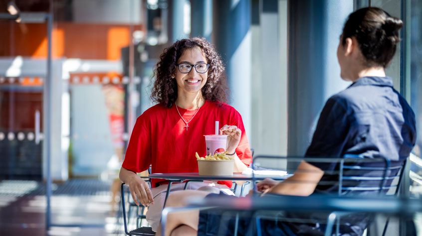 Two people sitting in a cafe, drinking coffee and talking