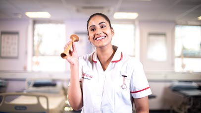 Person wearing a nurse's uniform holding some equipment