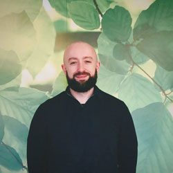 Man standing in front of a colourful background, smiling into the camera