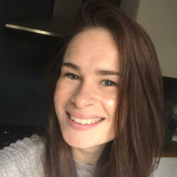 Woman with long brown hair, smiling at the camera