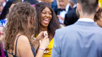 Photograph of student smiling surrounded by people