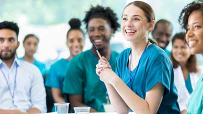 People in scrubs sat at desks in a seminar