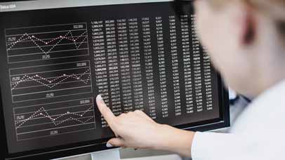 Person pointing to a screen filled with data