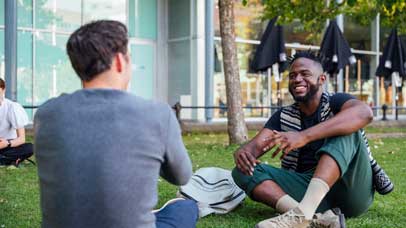 Two men sitting on a lawn and laughing