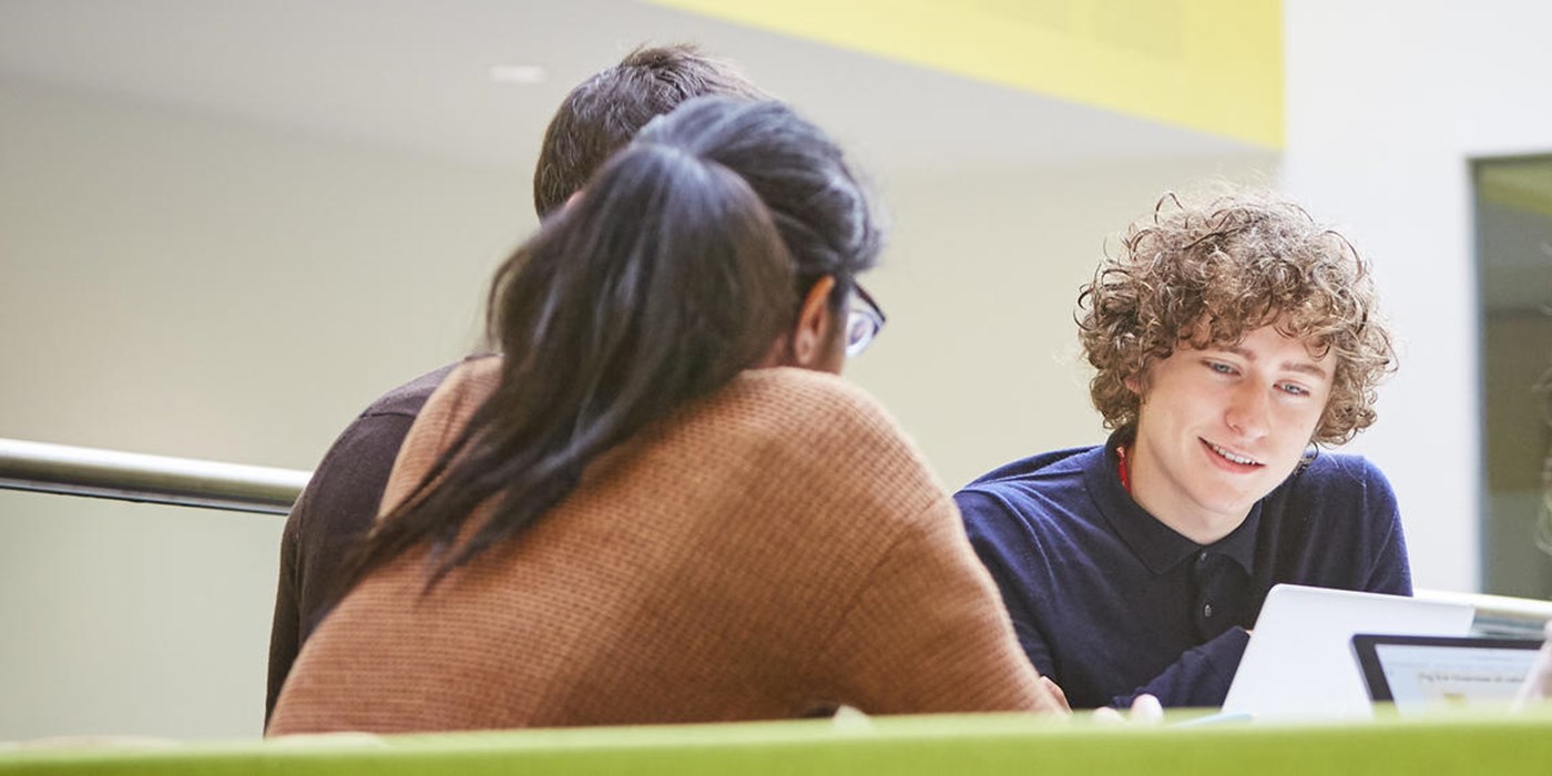 Students gathered round a table talking and laughing