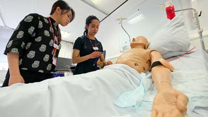 Two students working with a medical dummy.