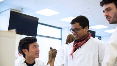 Three students in lab coats talking