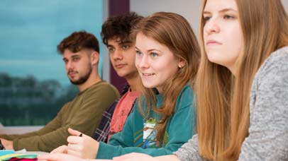 Four students sat at a table, focussing on a point off camera