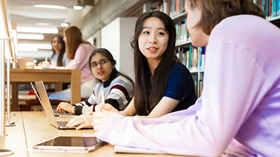 Three students discussing something in a library