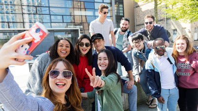 Students taking a selfie on Leicester campus in front of the David Wilson library