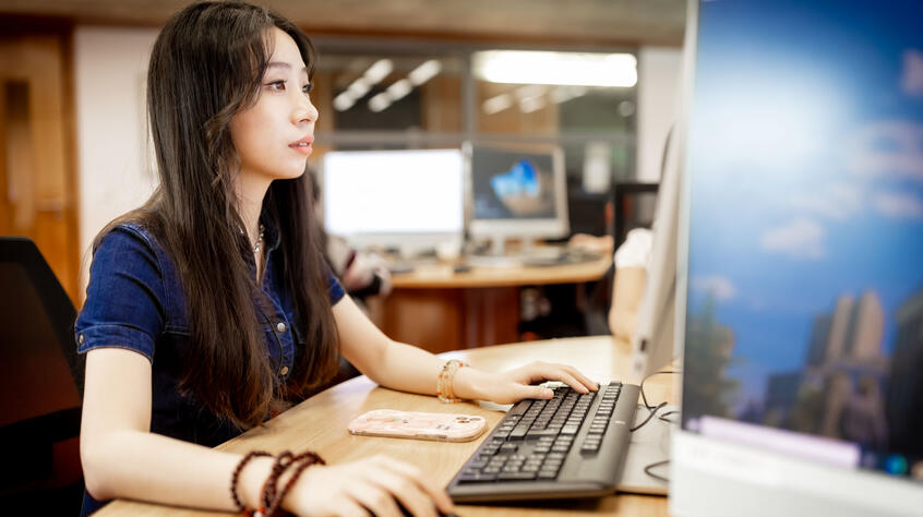 female student sat in a room working on a computer