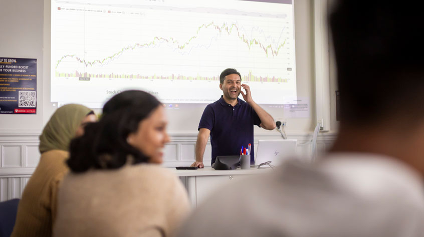 Lecturer smiling whilst teaching a class.