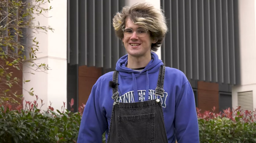 Student standing in front of the George Davis building on campus