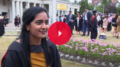 Student in graduation robes being interviewed outside De Montfort Hall.