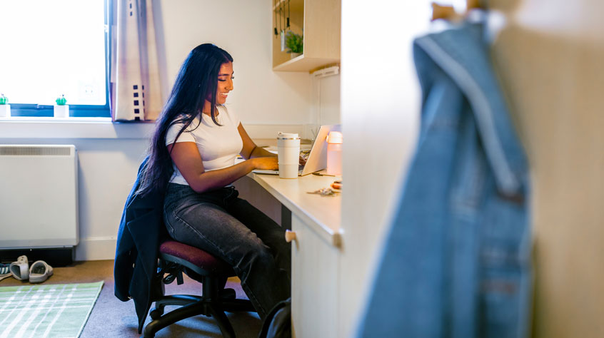 Person sitting at a desk in a university halls.