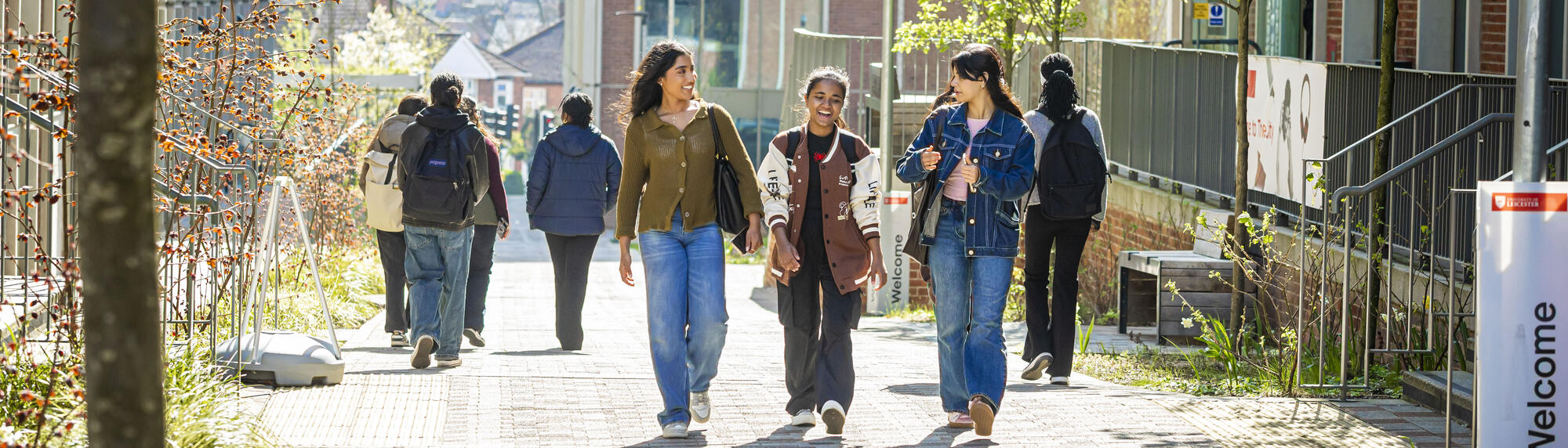 Three female students talking and walking through University of Leicester campus.