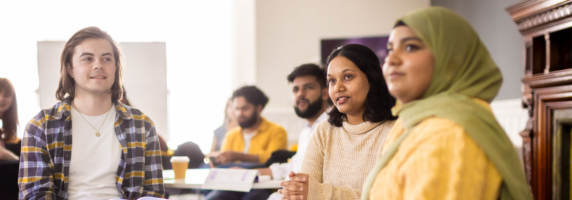 Three students listening to someone talk 