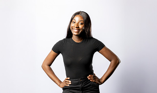 A young woman wearing a black t-shirt and black pants standing confidently