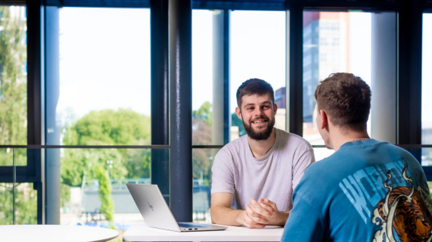 Two male students sat at a table talking