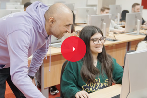 Smiling student working at a desk with academic supervision