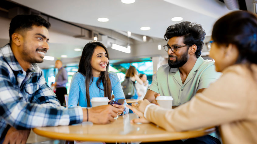 Students sitting around a table, talking and laughing