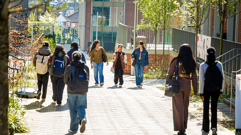 A number of people walking through a university campus