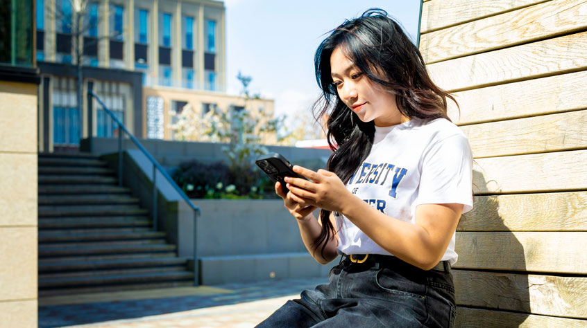 Woman looking at her phone whilst sitting on a bench.