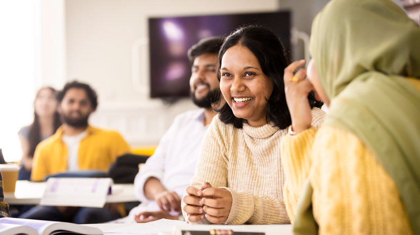 Students sitting in a classroom and smiling.