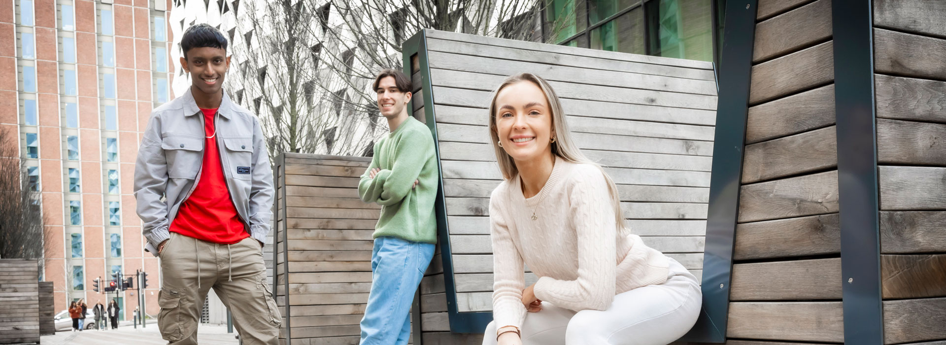 Students sitting on benches and posing for photos on Leicester campus.