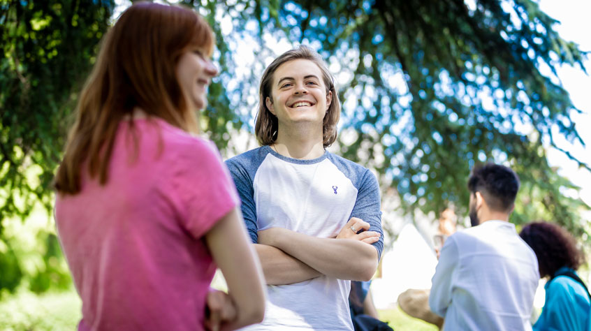 Students standing under a tree smiling