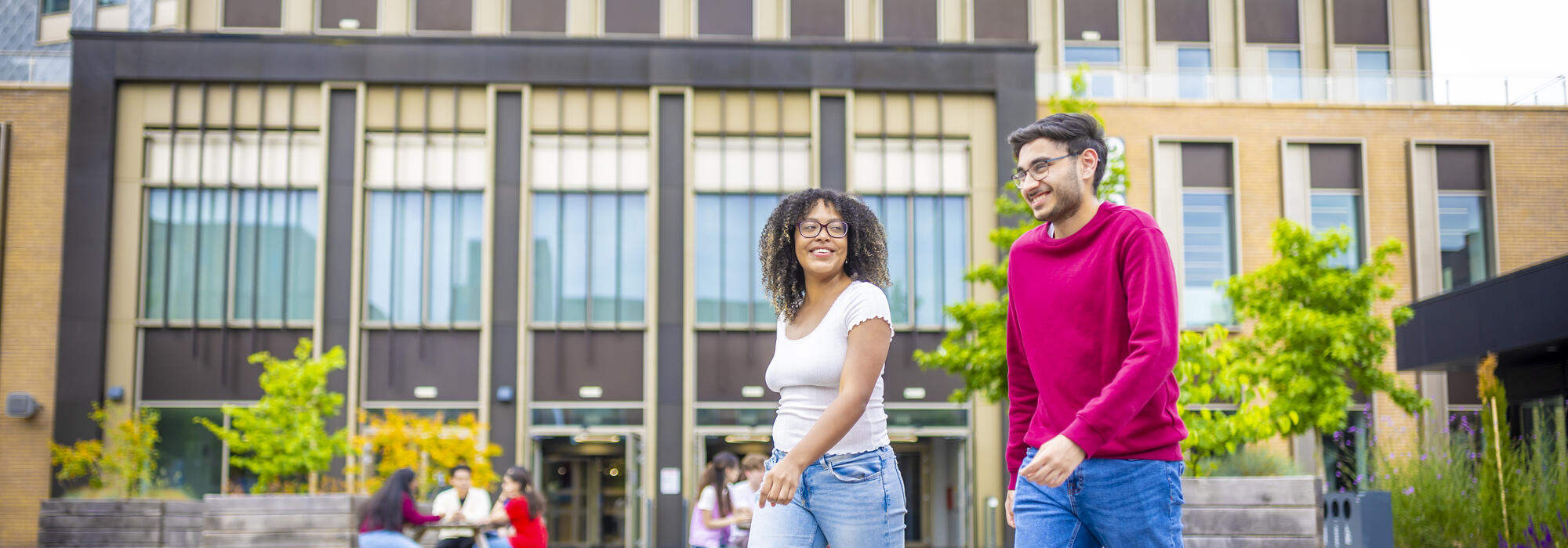 Two students walking and smiling, while in conversation with each other.