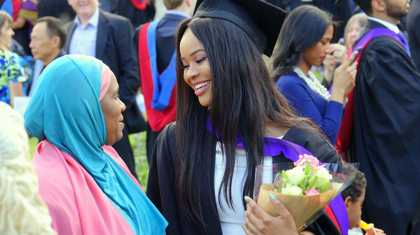 Student at graduation with family member.