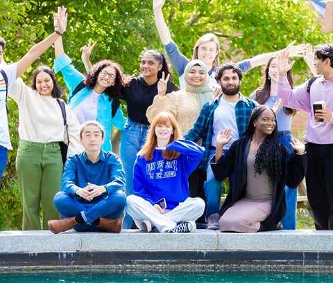 A group of University of Leicester students, some sat down and some stood up, next to a water feature on University campus