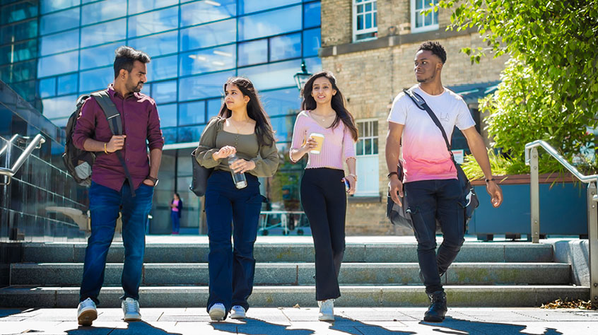 Four students walking through the University of Leicester campus