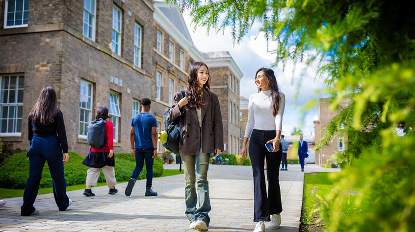 Two students walking through the University of Leicester campus