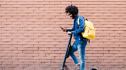 student checking phone on electric scooter