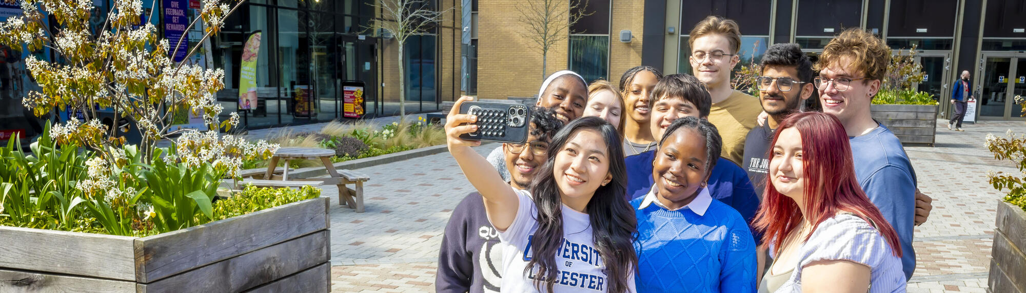 A group of students standing outside Sir Bob Burgess building, taking a selfie together.