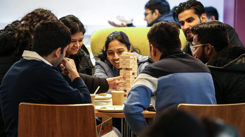 Group of people sat around a table, playing Jenga.