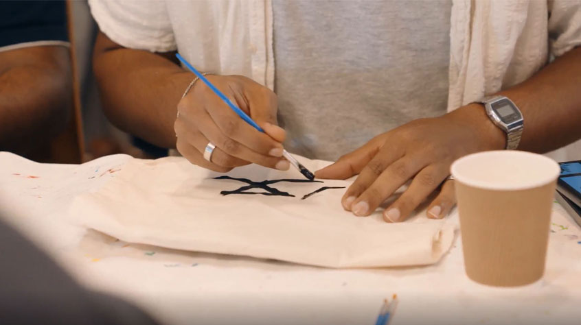 Close up of a person painting with black paint. 